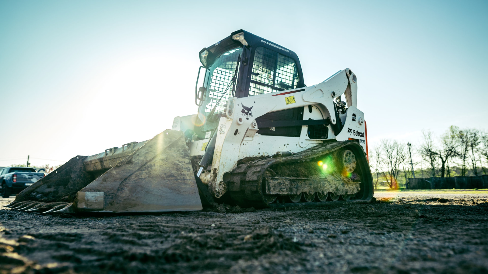 Track loader with a wide bucket sitting on freshly graded dirt at a jobsite