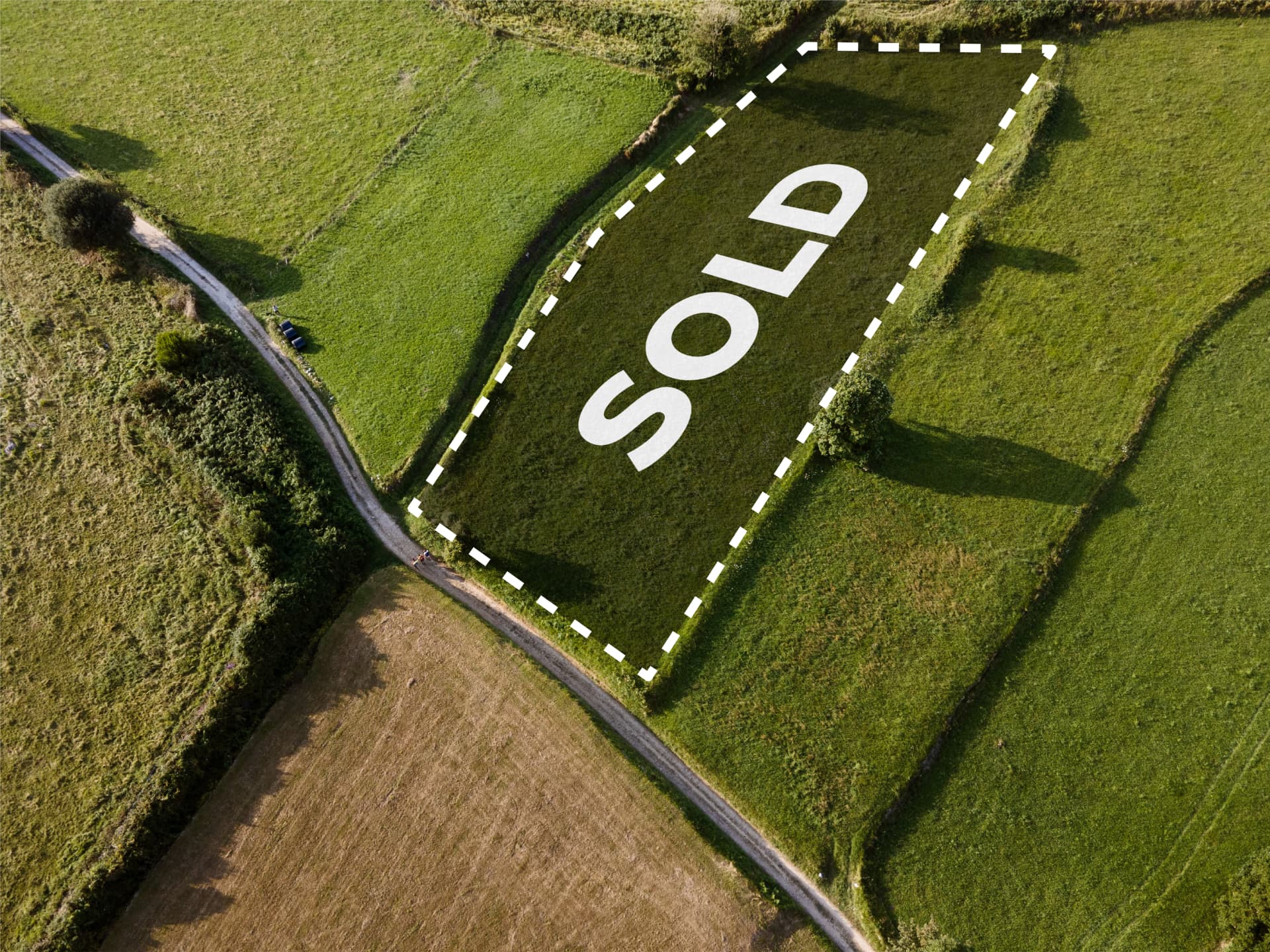 Aerial view of a sold land parcel outlined by a dashed border