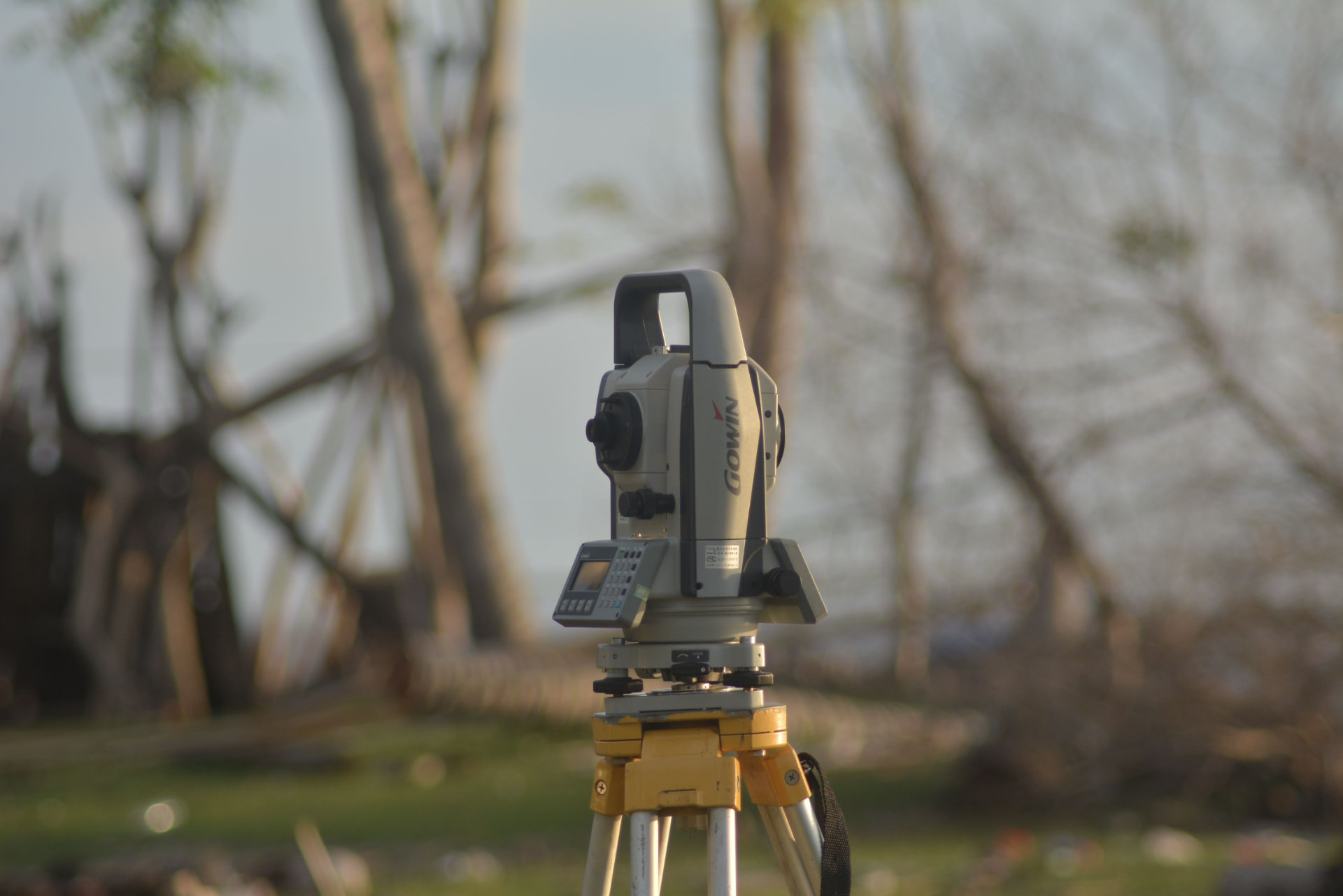 Survey total station mounted on a tripod on a cleared tract at golden hour
